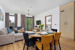 Una sala moderna con sofá, mesa de comedor, sillas, televisor y armario.