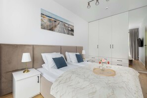 Un dormitorio con cama, mesitas de noche, un armario grande y un cuadro en la pared.
