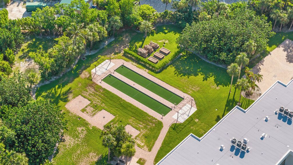 Una vista aerea di un'area paesaggistica con una piscina rettangolare, circondata da vegetazione e alberi.