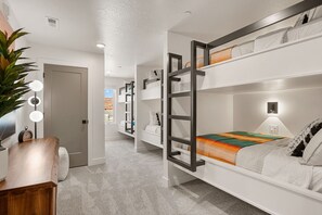 Une chambre moderne avec des lits superposés, un bureau, une lampe et une plante.