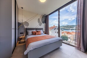 Ein modernes Schlafzimmer mit einem großen Bett, Blick auf die Stadt und einem großen Fenster.