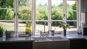 A kitchen with a large window, a sink, and a coffee maker. - Challens Yarde is a large double fronted cottage, providing spacious, bright, and airy accommodation (Midhurst)