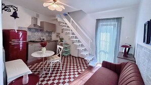 Ett kompakt bostadsutrymme med kök, matplats och en trappa som leder upp till en övre våning.