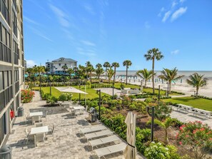 A hotel courtyard with outdoor seating, a grill, and a view of the beach.