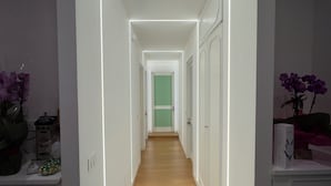 A narrow hallway with a wooden floor, white walls, and a green door at the end.