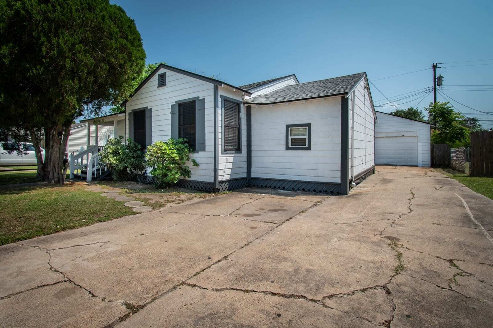 A two-story mobile home with a garage, a driveway, and a tree in the yard.