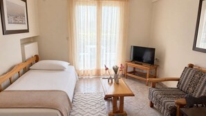Habitación de hotel con cama, sofá, televisor sobre un mueble de madera y ventana con cortinas.