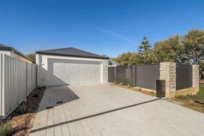 Une maison moderne avec garage, allée pavée et mur en pierre.