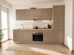 A modern kitchen with a built-in oven, a sink, and a coffee machine. - 1-Bedroom Apt 30m from Sea | AC | Terrace | Bike Friendly + Box (Finale Ligure)