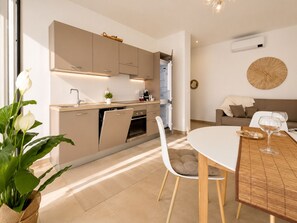 A modern kitchen with a dining area, a sofa, and a coffee table. - 1-Bedroom Apt 30m from Sea | AC | Terrace | Bike Friendly + Box (Finale Ligure)