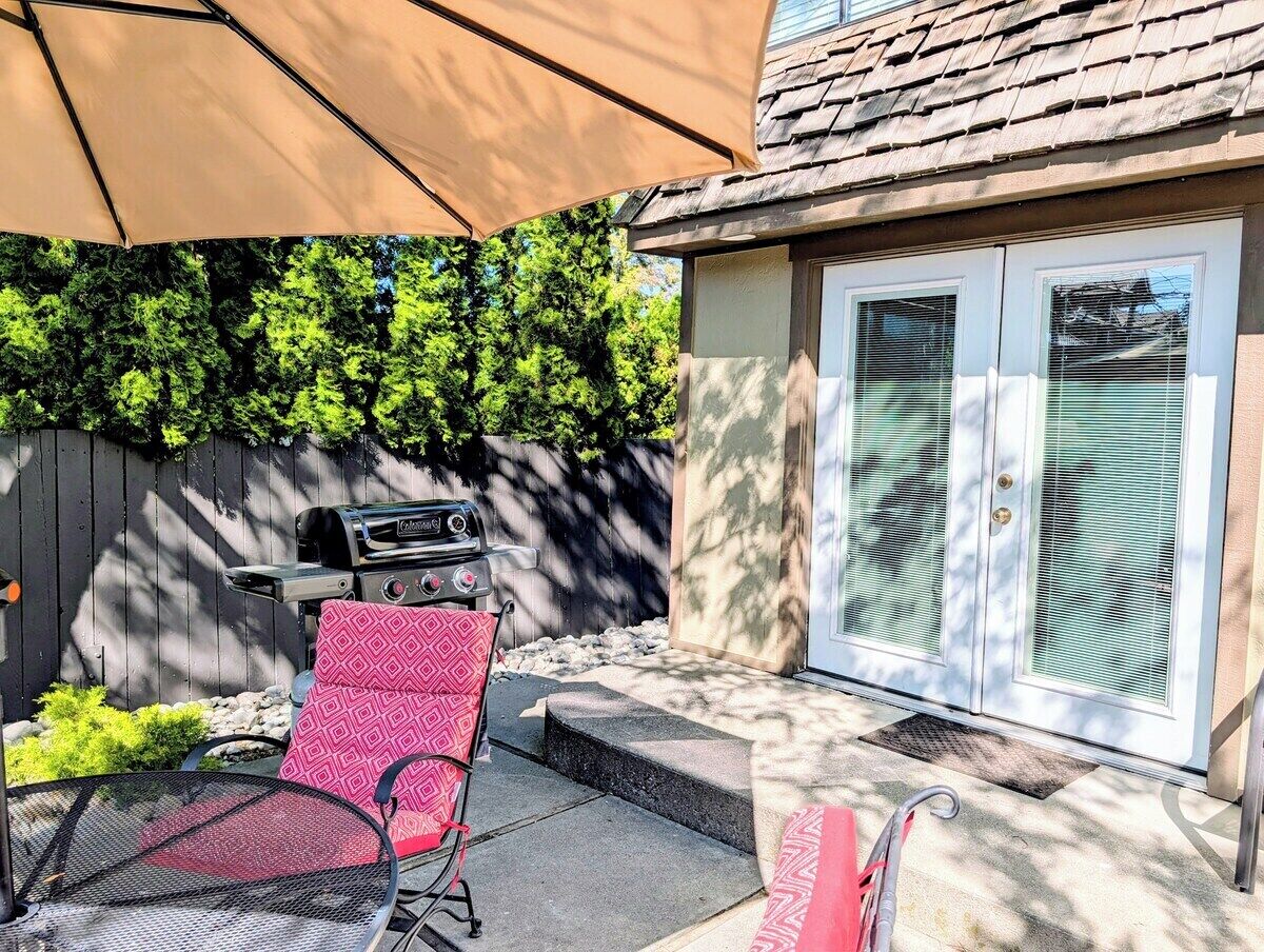 A patio area with a grill, a red chair, and a covered seating area.
