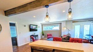 Une cuisine moderne dotée d’un îlot central, de planchers en bois et de luminaires suspendus.
