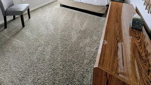 Une chambre à coucher avec un lit, une chaise, une table de chevet, un miroir et une fenêtre avec des stores.