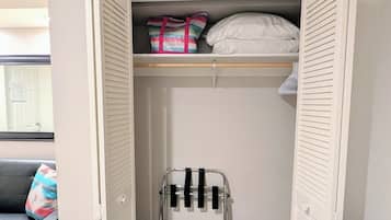 Un dressing avec un miroir, une tringle à vêtements et une étagère où sont pliés des vêtements.
