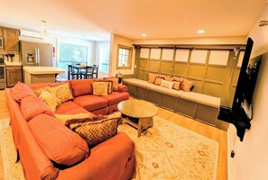 A living room with a sectional sofa, a round coffee table, and a built-in bench with cushions.