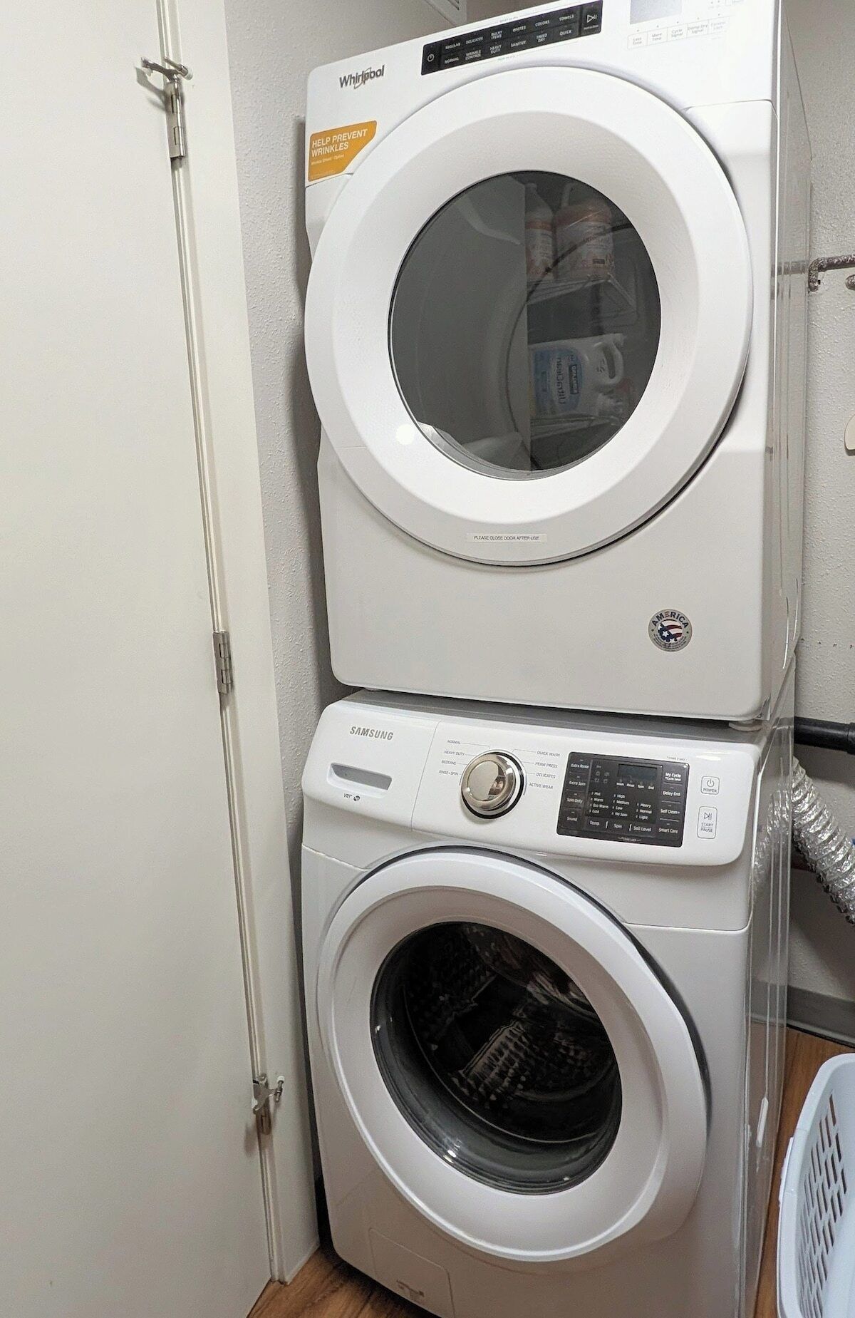 En stabling af vaskemaskine og tørretumbler med Samsung-mærke, Whirlpool-logo og klistermærke med teksten 'FOREBYG RYNKER'.