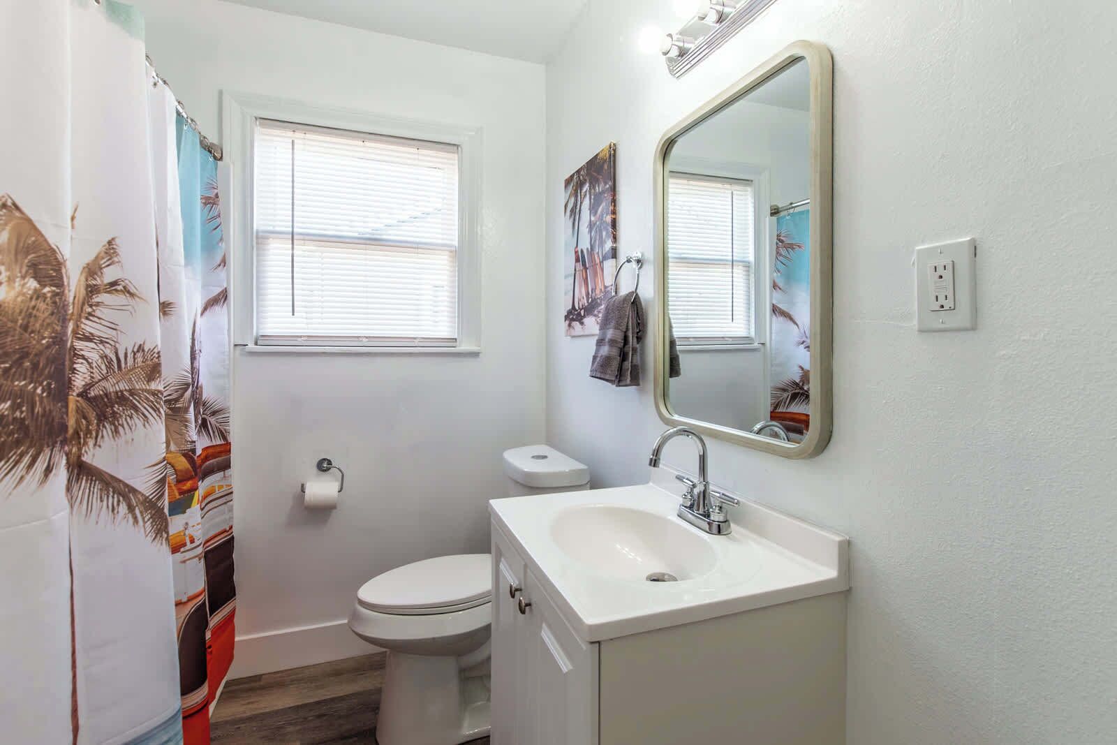 A bathroom with a toilet, sink, and shower curtain.