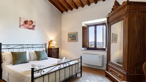 Un dormitorio con cama, armario de madera, ventana y radiador.