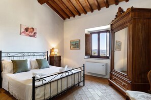 Un dormitorio con cama, armario de madera, ventana y radiador.