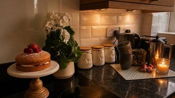 A kitchen counter with a cake, jars, a coffee maker, and a candle.