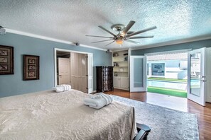 A bedroom with a bed, a ceiling fan, a door leading to a balcony, and a view of the outside. - Sleeps 28 - Ocean View - Pearl on Ocean Dr, Combined Estate (Corpus Christi)
