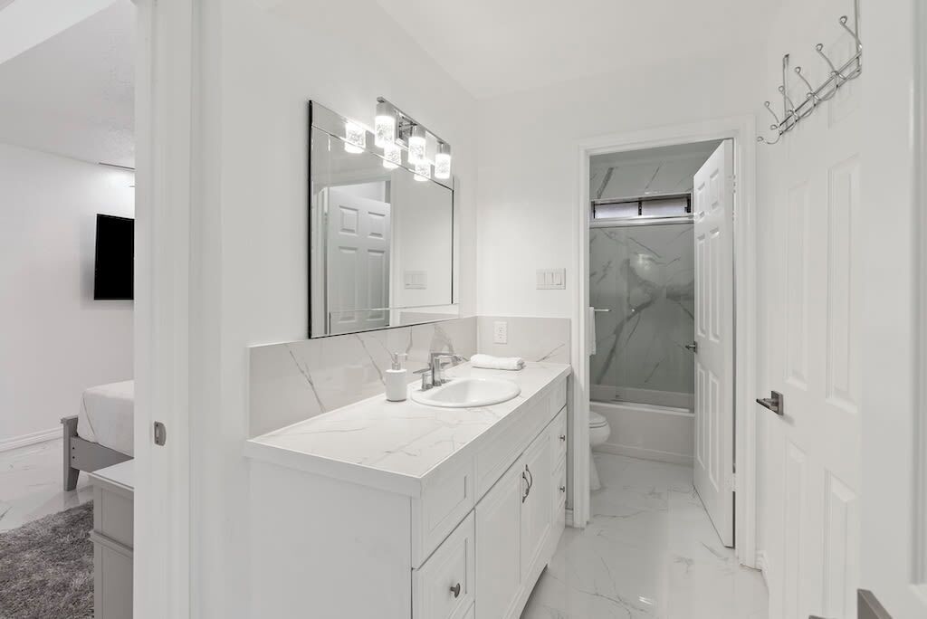 Une salle de bain moderne avec un grand miroir, un lavabo et une douche.
