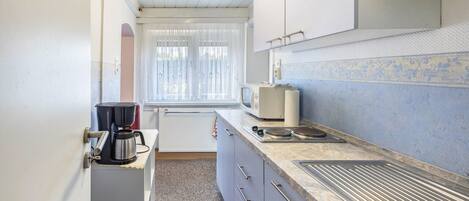 A compact kitchen with a coffee maker, a microwave, and a sink.