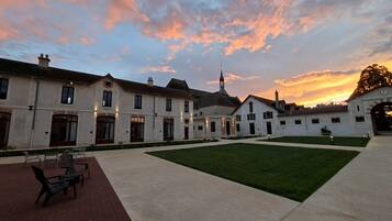 A courtyard with a lawn, outdoor seating, and a building with a clock tower.