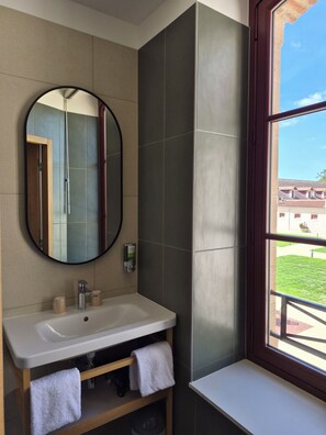 A bathroom with a round mirror, a sink, and a window. - L'Hostellerie du Haras (La Porte du Der)