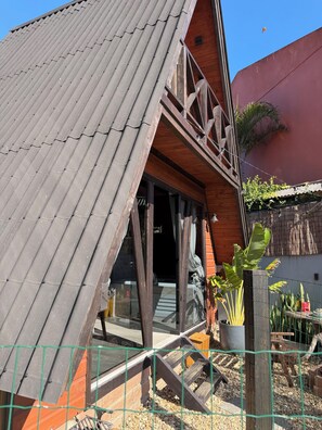 Ein Gebäude mit geneigtem Dach, Holzfassade und einer sichtbaren Treppe, die zu einem Eingang führt.