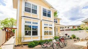 A two-story house with a covered porch, a garage, and a bicycle parked outside. - Spacious 4-bedroom home with private beach,  dock, large yard, outdoor shower. (Kelowna)