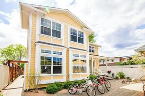 A two-story house with a covered porch, a garage, and a bicycle parked outside. - Spacious 4-bedroom home with private beach,  dock, large yard, outdoor shower. (Kelowna)