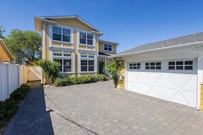 Une maison à deux étages avec un garage, une allée pavée et un petit jardin.