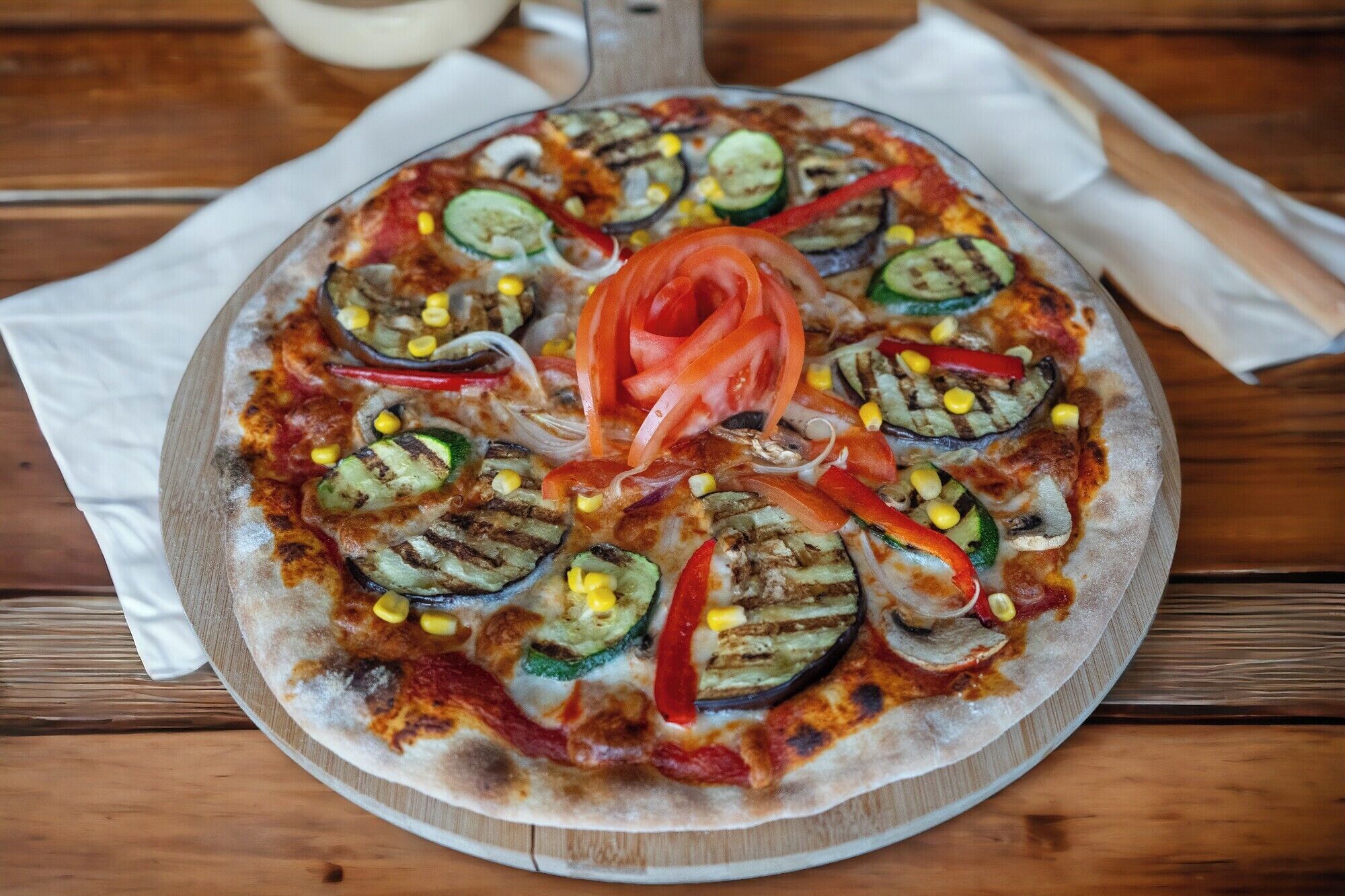 Una pizza sobre una mesa de madera con un mantel blanco debajo.