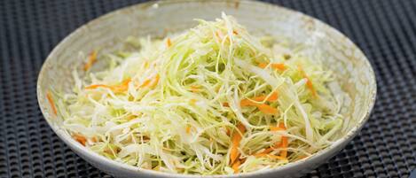 Un plato de ensalada de col sobre una superficie texturizada.