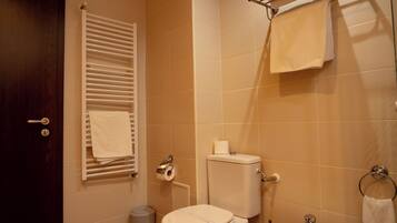 Een badkamer met toilet, bidet, handdoekrek en prullenbak.
