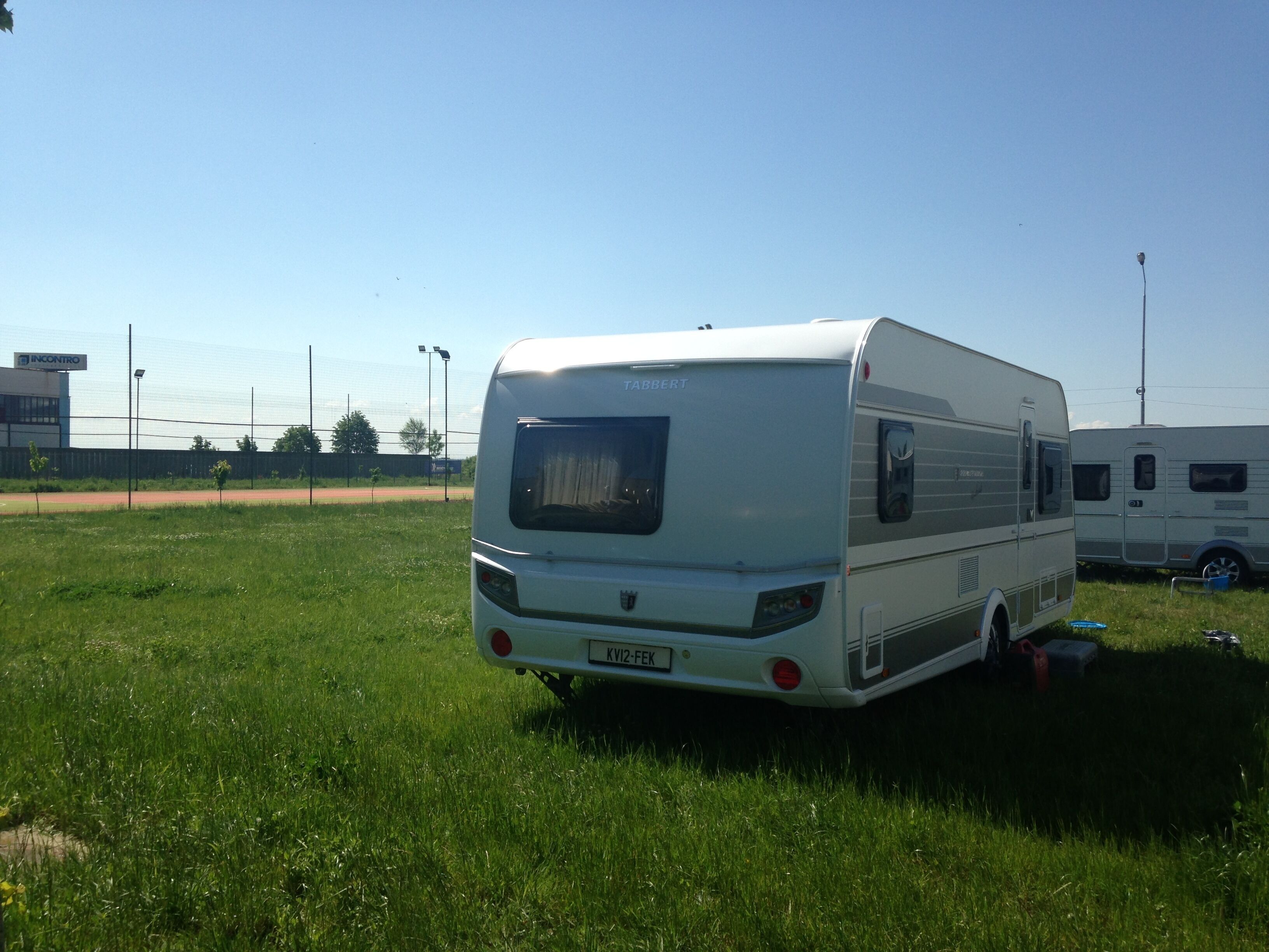 A white RV parked in a grassy field with a clear sky.