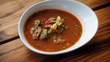 A bowl of stew with meat and vegetables on a wooden table.