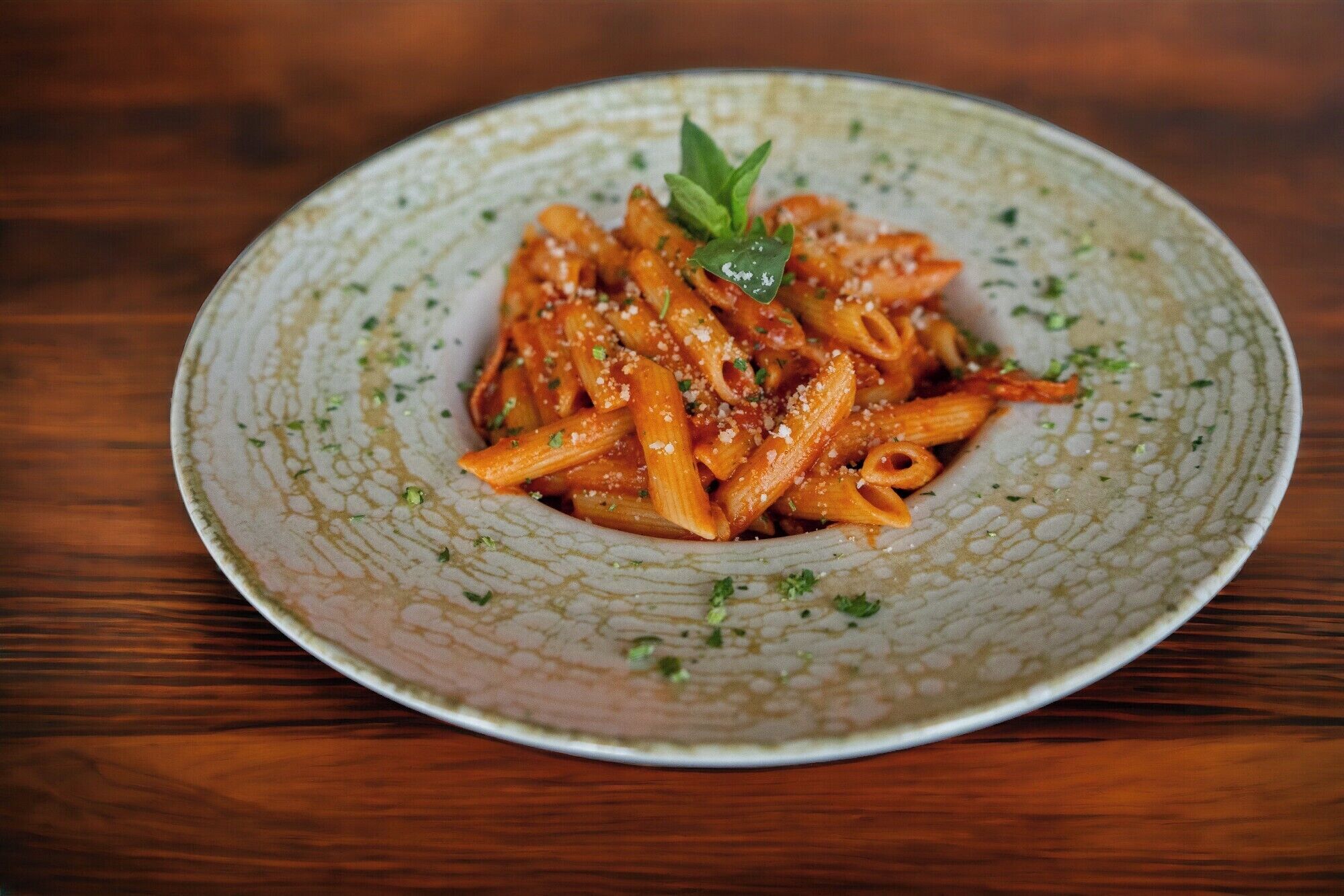 Un plato de pasta con decoración, sobre un plato de cerámica con textura.