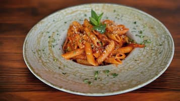 Un plato de pasta con decoración, sobre un plato de cerámica con textura.