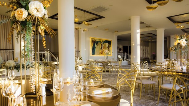 Un comedor lujoso con mobiliario con detalles dorados, una elegante vajilla y un cuadro grande en la pared.