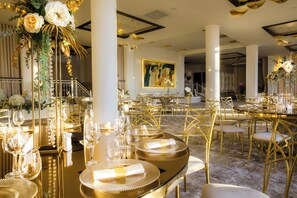 Un comedor lujoso con mobiliario con detalles dorados, una elegante vajilla y un cuadro grande en la pared.