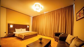 Una habitación de hotel con cama, sofá, mesa de centro y cortina.
