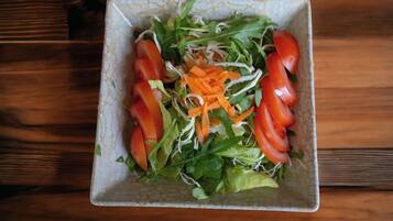 A square plate with a salad on a wooden table.
