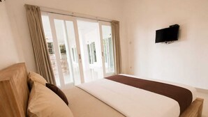 Une chambre à coucher avec un lit, un téléviseur et une porte-fenêtre coulissante.
