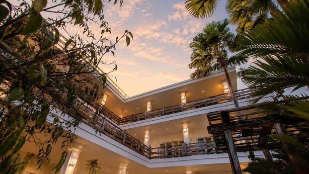 Un hôtel à plusieurs étages doté d’une cour intérieure, de balcons et d’une piscine.