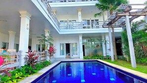Un hôtel doté d’une piscine centrale, de nombreux balcons et d’une végétation luxuriante.