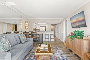 Ein modernes Wohnzimmer mit einem grauen Sofa, einem Couchtisch und einem gemusterten Teppich.