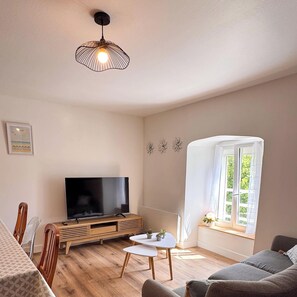 Ein Wohnzimmer mit Fernseher, Holzmöbeln, einem kleinen Tisch, einer Couch und einem Fenster mit Blick.
