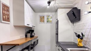 Ett modernt kök med vita skåp, en bänkskiva i trä, en kaffemaskin, en mikrovågsugn och ett handfat.